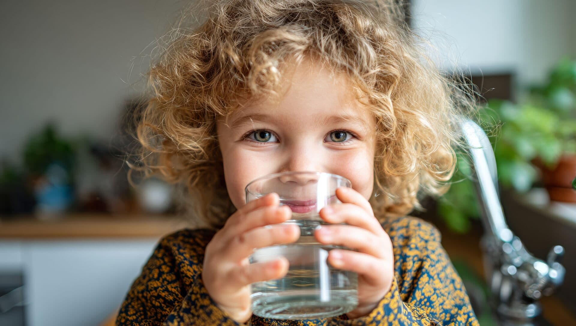 Child drinking clean filtered water in kitchen