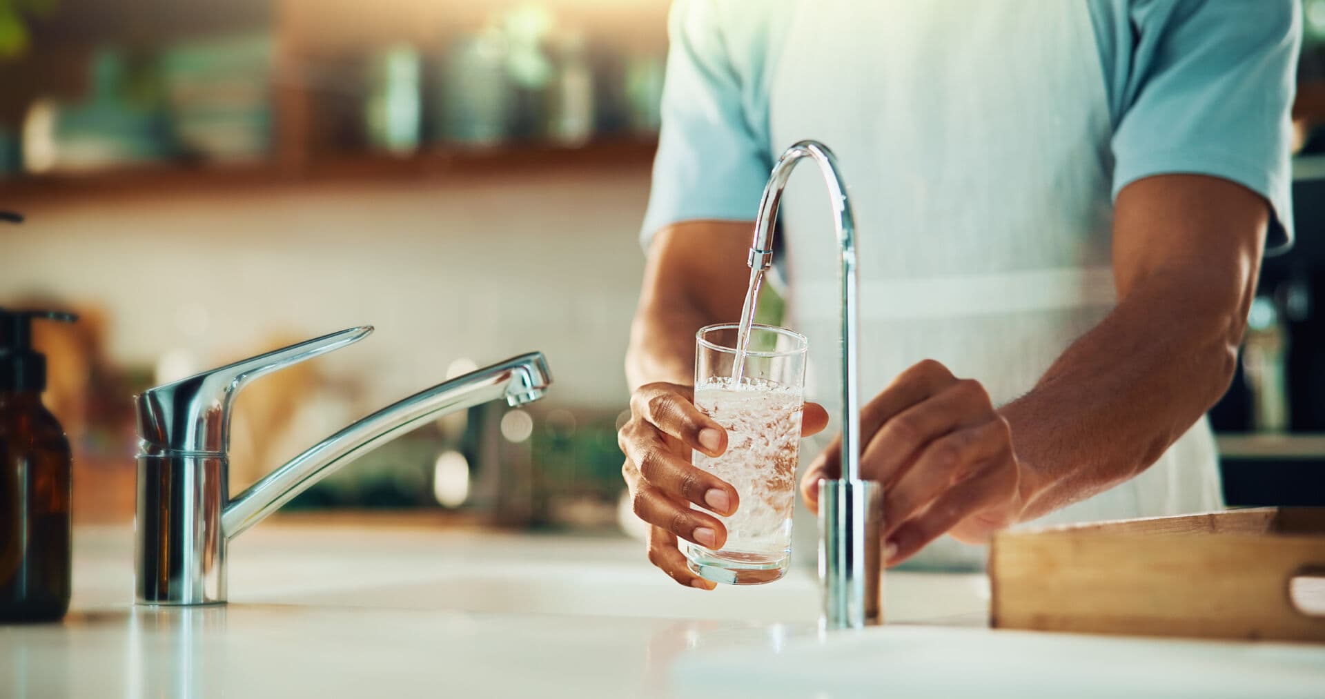Man using filtered water at kitchen faucet
